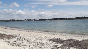 A beach with clear water, sandy shore, and distant buildings. - Charming apartment on the 1st floor, St Goustan port of Auray. (Auray)