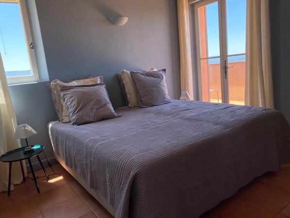Une chambre à coucher avec un grand lit, une table de chevet et une fenêtre donnant sur l’extérieur.