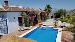 Un área de piscina con sillones, una pérgola y vistas a montañas.