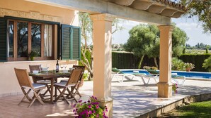 A covered outdoor dining area with a table and chairs, a pool, and a view of the surrounding landscape. - Country house with private pool and panoramic views and accessible (Santa Margalida)