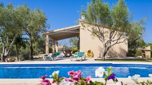 A poolside area with a pergola, lounge chairs, and a clear blue pool. - Country house with private pool and panoramic views and accessible (Santa Margalida)