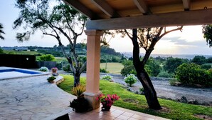 A covered outdoor area with a stone pool, potted plants, and a view of a landscaped garden and distant hills. - Country house with private pool and panoramic views and accessible (Santa Margalida)