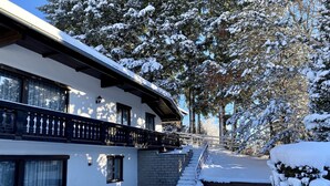 A snow-covered building with a balcony and steps leading to a door. - Hillside villa with private pool (Altmünster)