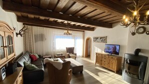 A living room with a wooden ceiling, a fireplace, a television, and a sofa. - Hillside villa with private pool (Altmünster)
