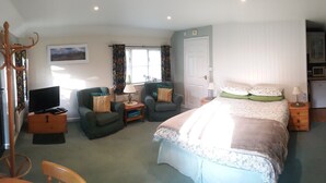 A bedroom with a bed, two chairs, a television, a desk, and a bookshelf. - Amberfold Lodge, Heyshott near Midhurst (Midhurst)