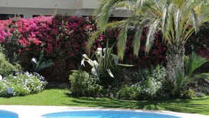 A swimming pool with a decorative edge, surrounded by lush greenery and flowering plants. - Vilamoura, Good location with sea view and swimming pools (Vilamoura)