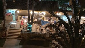 An outdoor seating area with umbrellas and tables, a stone staircase, and a building with a tiled roof in the background. - Vilamoura, Good location with sea view and swimming pools (Vilamoura)