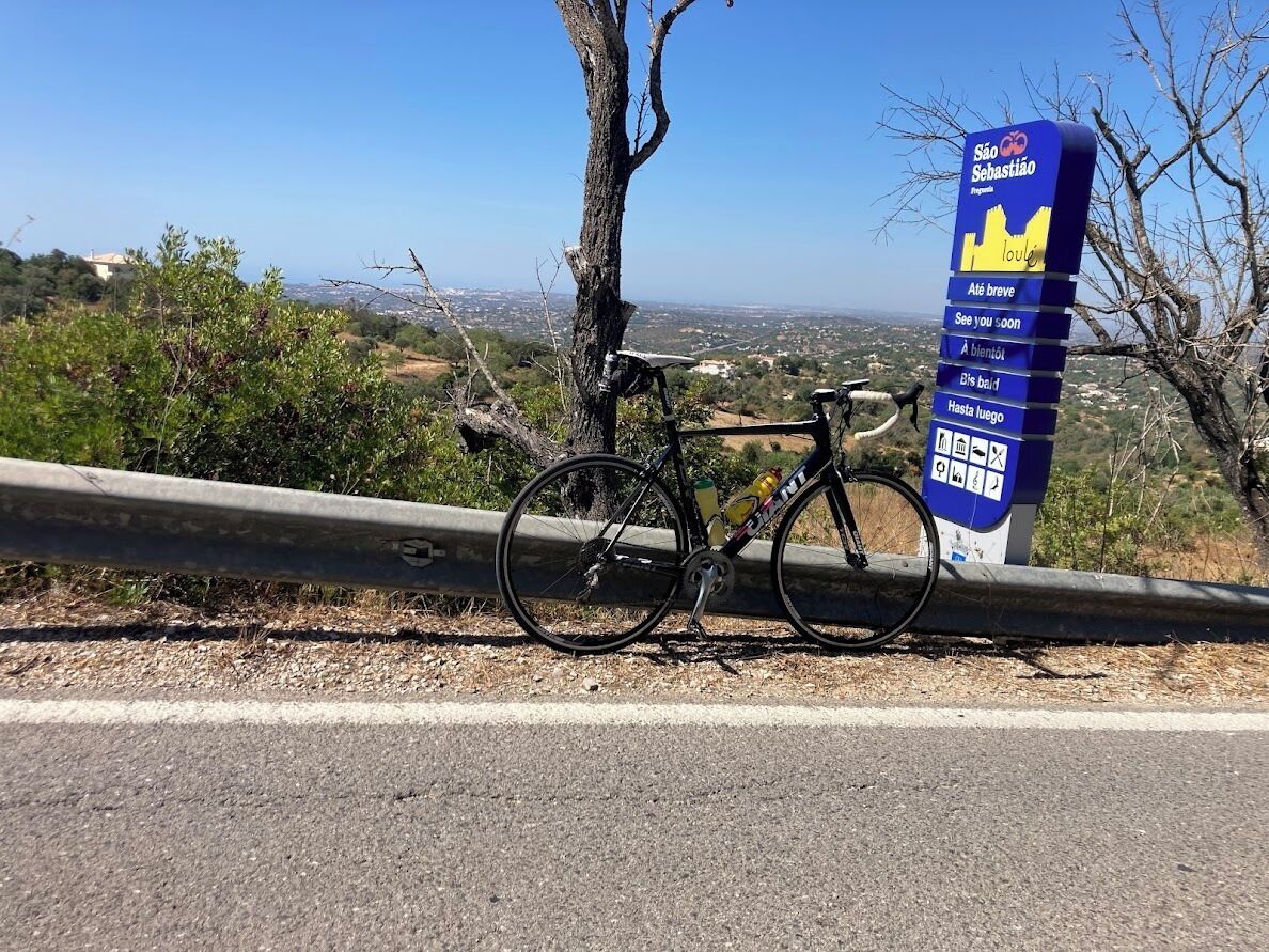A bicycle parked next to a sign with the text "São Sebastião" and "Aldeia Breve."