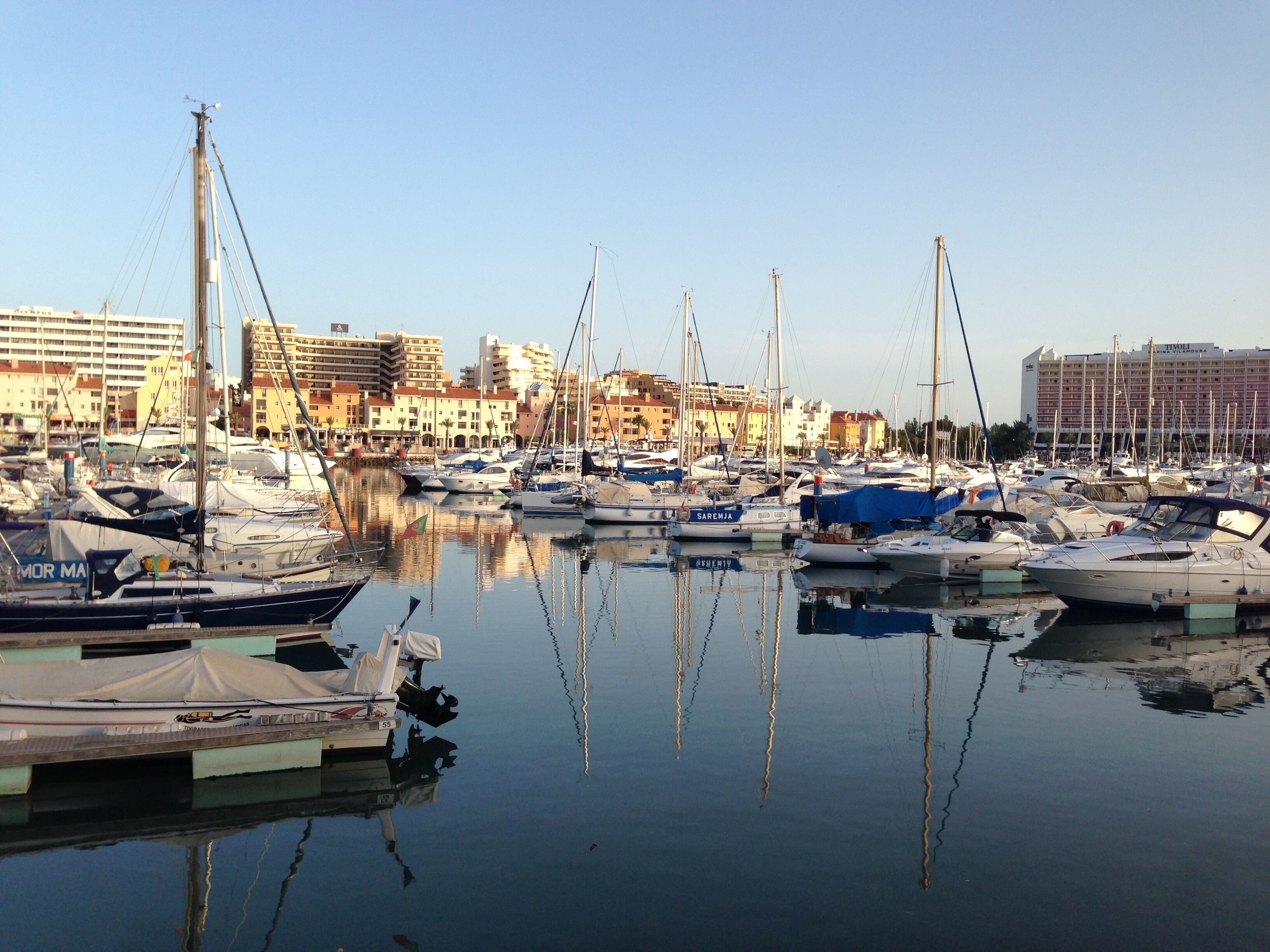 A marina with numerous boats docked, surrounded by buildings.