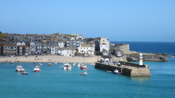 A coastal town with a sandy beach, a lighthouse, and numerous boats. - Harbour View Apartment has stunning views of St Ives harbour and beaches. (St Ives)