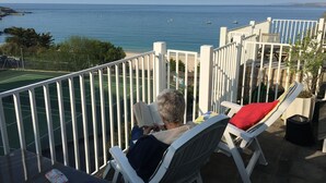 A balcony with a view of the sea, a tennis court, and a white railing. - Harbour View Apartment has stunning views of St Ives harbour and beaches. (St Ives)
