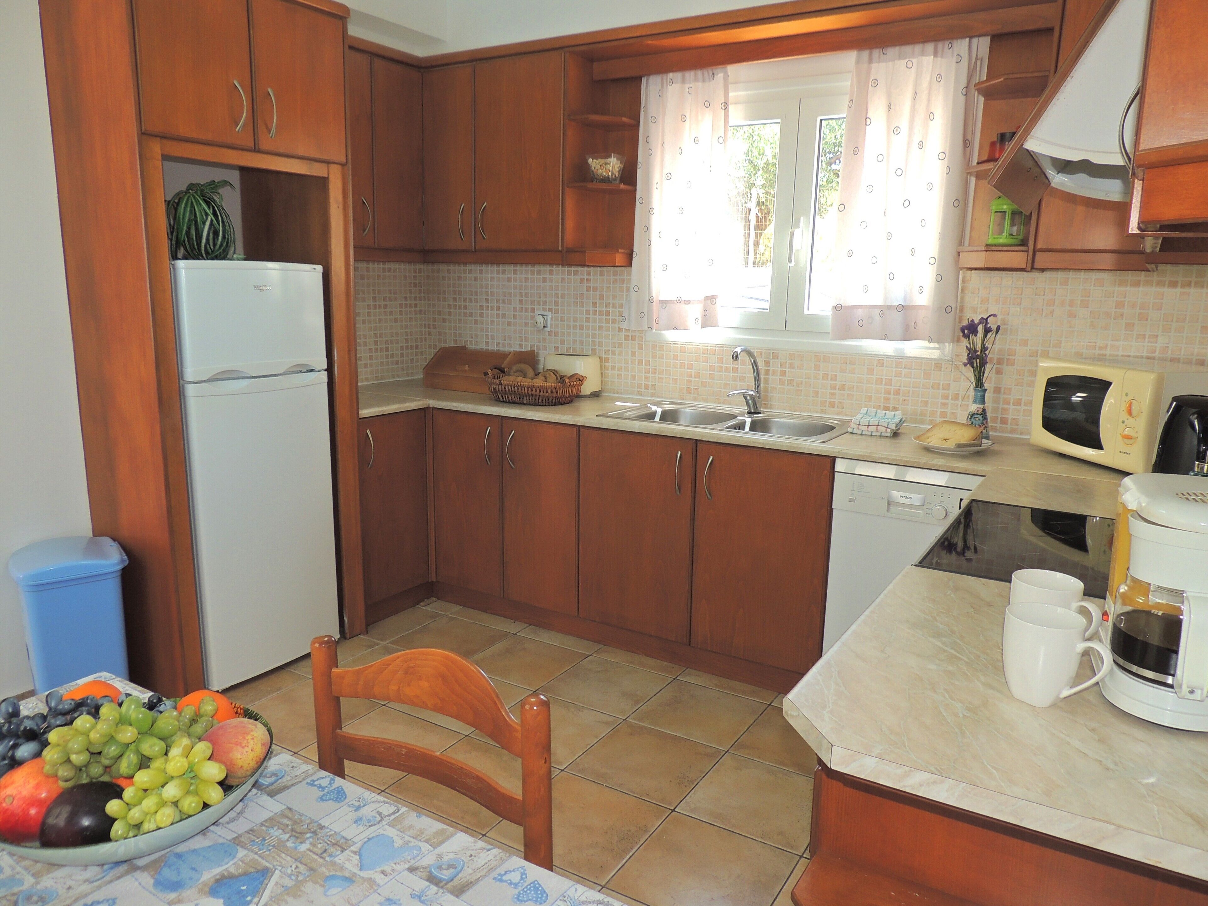 A compact kitchen with wooden cabinets, a refrigerator, a sink, and a microwave.