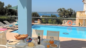 Une table au bord de la piscine avec de la nourriture et des boissons, une vue sur la mer et des chaises longues.