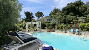 A swimming pool with lounge chairs and a pergola.