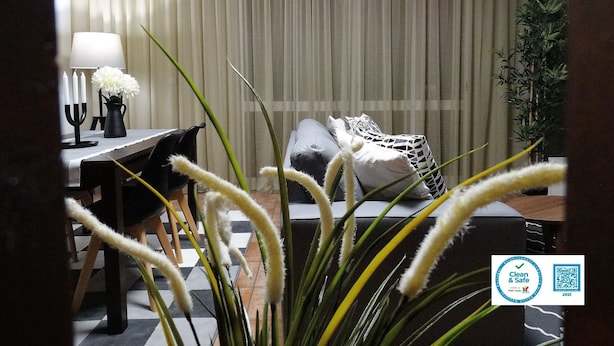 Et hotelværelse med en seng, et skrivebord med lampe og en potteplante.