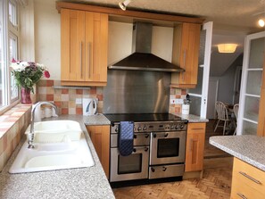 Equipped with a double oven, sink, and stainless steel range hood, this kitchen offers ample cooking space.