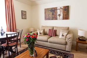 Cozy living space with a sofa, coffee table, dining table, and artwork.