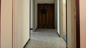 A hallway with a tiled floor, wooden door frames, and a ceiling fan.