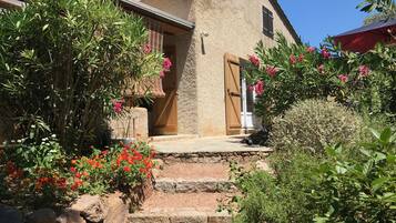 Un bâtiment rustique doté d’une façade en pierre, d’une porte en bois et d’un petit porche avec des marches menant à l’entrée.