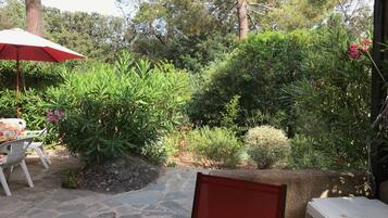 Un espace patio avec un sol en pierre, une table entourée de chaises et un parasol rouge.