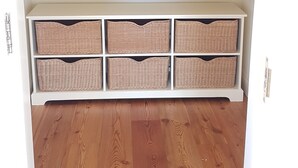A closet with multiple shelves and hanging space, wooden flooring, and a white door.