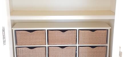 A closet with multiple shelves and hanging space, wooden flooring, and a white door.