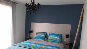 Une chambre à coucher avec un lit, deux tables de chevet, un lustre et une porte en bois.