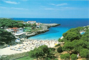 A coastal town with a beach, rocky breakwater, and buildings with balconies overlooking the sea. - Villa With Private Pool Well Located (Ciutadella de Menorca)
