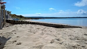 A sandy beach with a wooden walkway leading to a body of water.