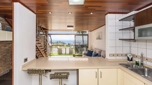 Une cuisine moderne donnant sur un balcon, avec un plafond en bois et un téléviseur encastré.