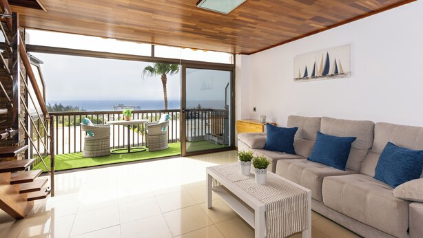 Un vaste espace de vie avec un balcon, un canapé, une table basse et un escalier.