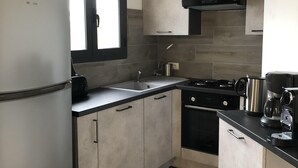 Una cocina compacta con refrigerador, estufa, lavamanos y armarios.