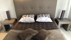 Un dormitorio con una cama grande, dos mesitas de noche y dos altavoces.
