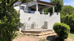Un edificio blanco con un porche cubierto y mesas al aire libre.