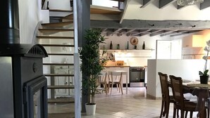 Un'ampia cucina con elettrodomestici moderni, una zona pranzo con sedie in legno e una scala che conduce a un piano superiore.
