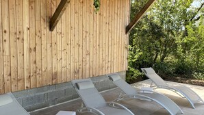 Un'area relax esterna coperta con quattro poltrone e una pianta pensile.