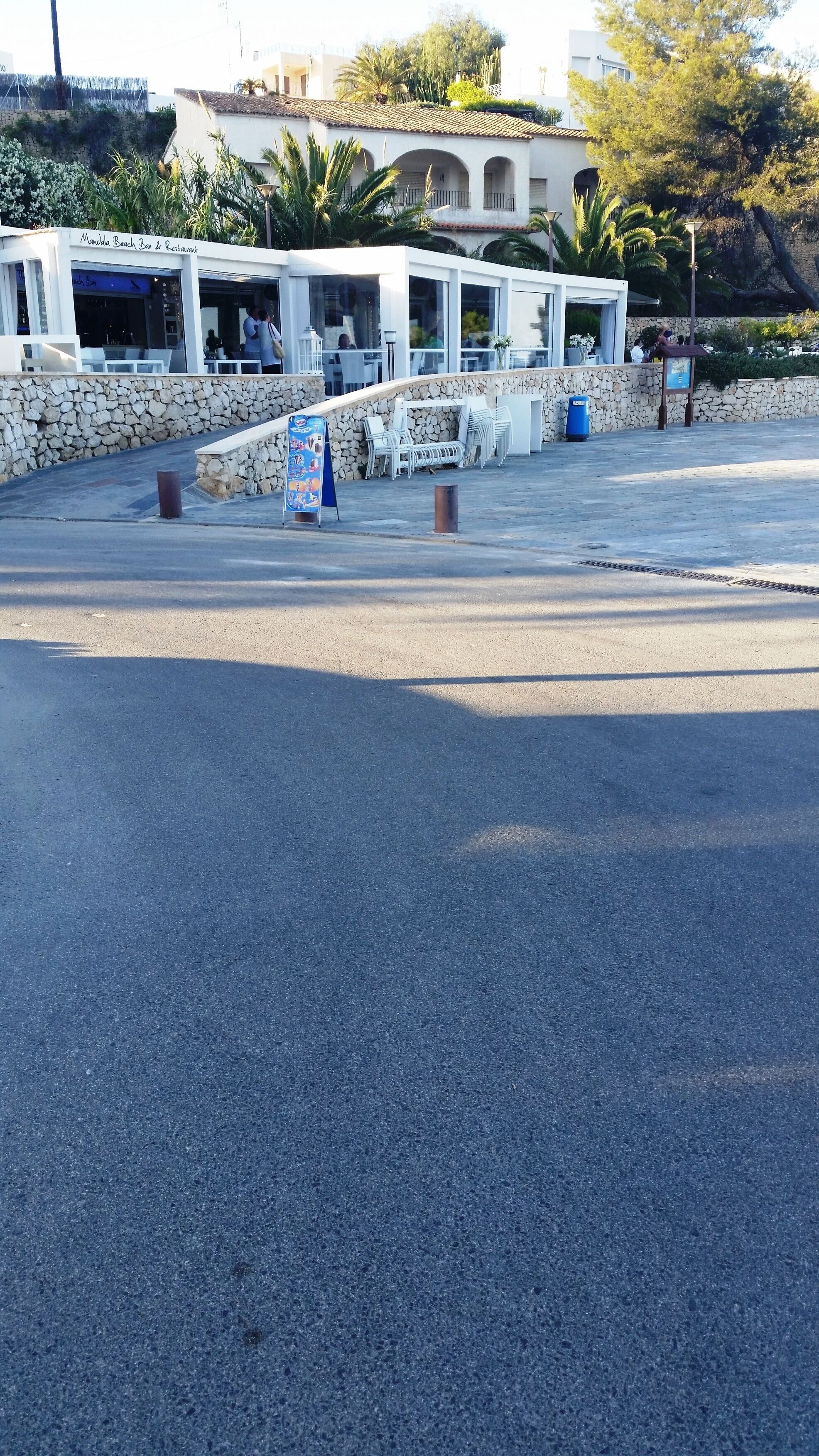 A beachfront restaurant with outdoor seating and a stone wall.