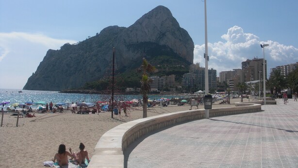 A beach with a large mountain in the background, a curved walkway, and beach umbrellas. - Villa Zsara very near La Fustera In its own grounds with private pool (Calp)