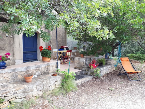 A stone house with a blue door, outdoor seating, and potted plants.