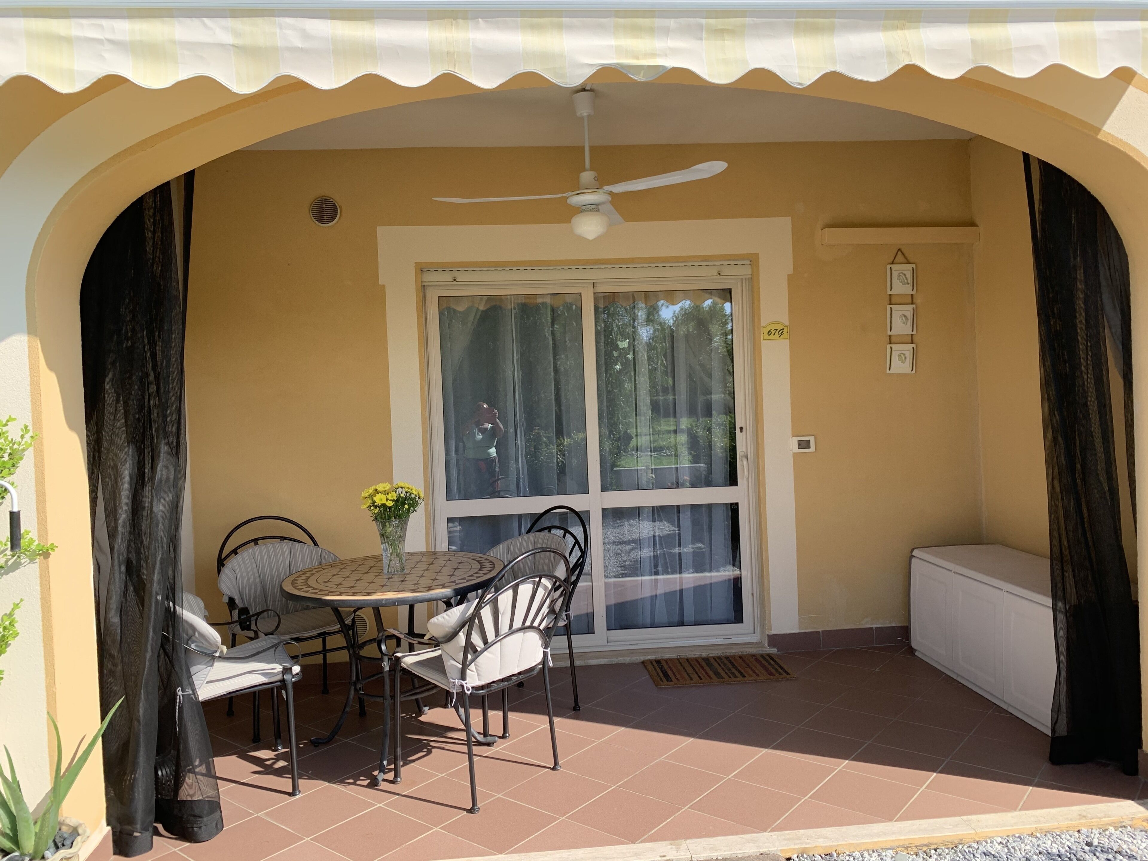 A patio with a round table and chairs, a ceiling fan, and a sliding glass door.
