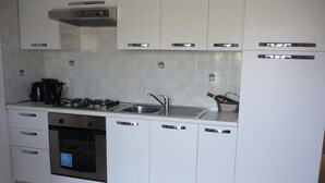 A modern kitchen with white cabinets, a stainless steel sink, a gas stove, and a dishwasher. - Spacious, modern ground floor apartment, private patio and garden, mosquito nets (Calabria)