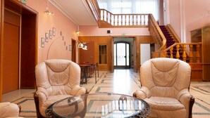 A hotel lobby with two leather armchairs, a glass coffee table, a staircase with wooden railings, and a door leading to another room. - Domaine La Rosière - Villa for 50 people Indoor swimming pool, Tennis court, Cinema, etc. (Diemeringen)