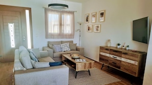 A living room with a sofa, a coffee table, a wooden cabinet, and a flat-screen TV mounted on the wall. - Luxury Detached Villa With Private Pool And Views Over The Sea (Afandou)