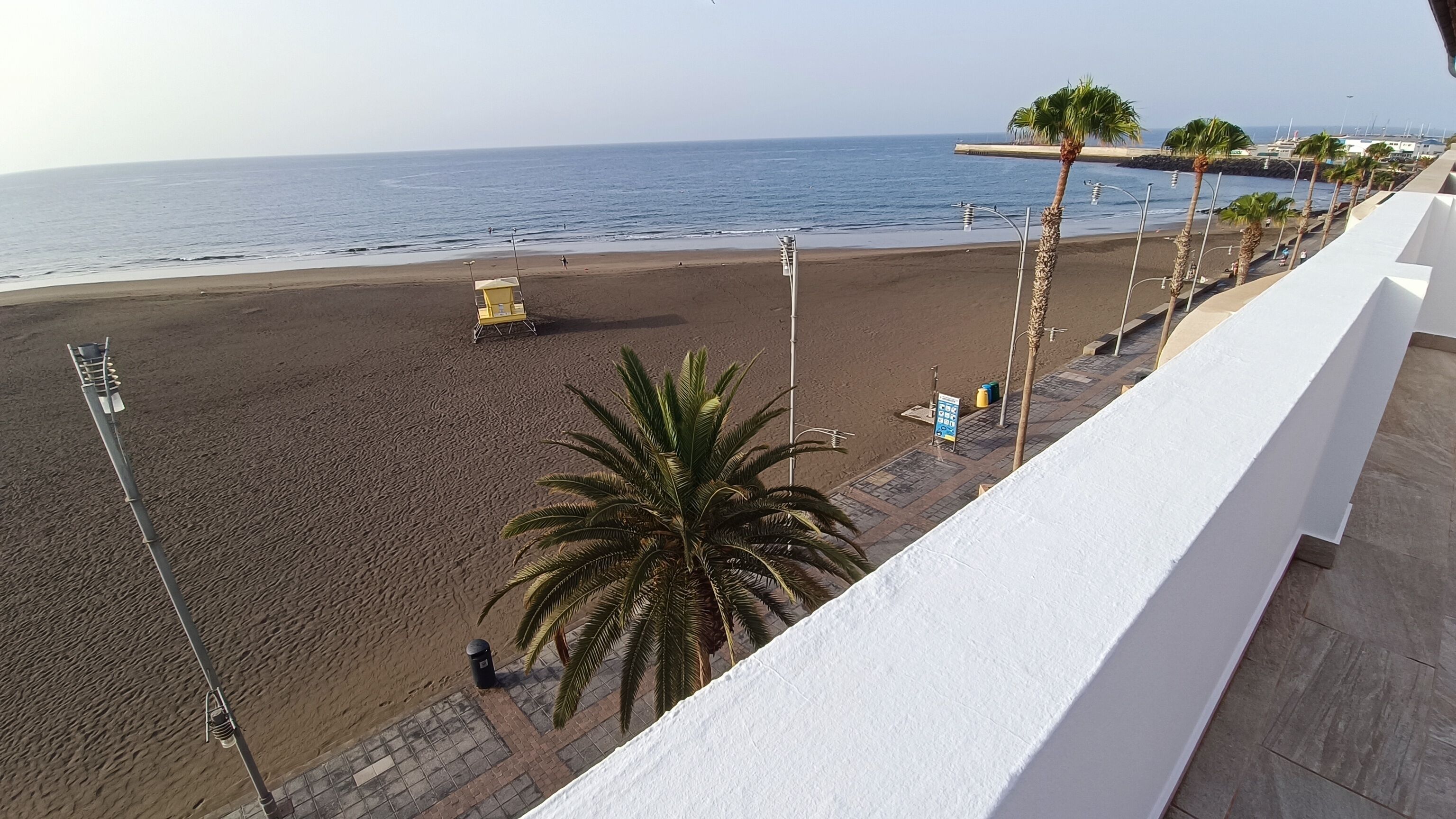 A beach with a lifeguard tower, palm trees, and a clear view of the ocean.