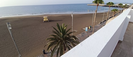 A beach with a lifeguard tower, palm trees, and a clear view of the ocean.