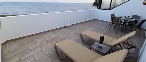 Een terras met uitzicht op zee, met lounge stoelen, een tafel en een eethoek.