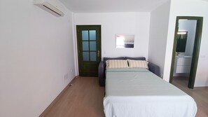 A bedroom with a bed, a door, a mirror, and a wall-mounted air conditioning unit. - Front line beach penthouse with spectacular views (Gran Tarajal)