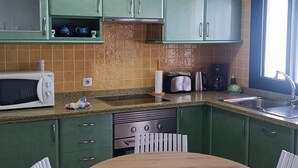 Eine Küche mit grünen Schränken, einer Mikrowelle, einem Toaster und einem Spülbecken.