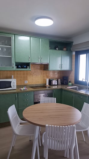 A kitchen with green cabinets, a microwave, a toaster, and a sink.