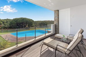 A balcony with a view of a swimming pool and surrounding greenery.